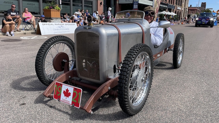 Une homme dans une voiture miniature dans une foule.