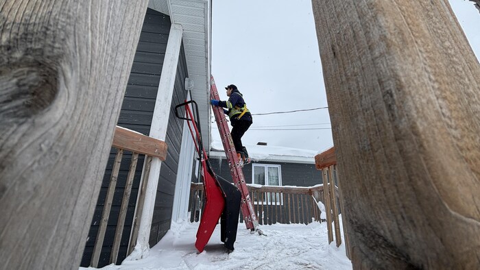 Une personne monte une échelle à l'extérieur en hiver.