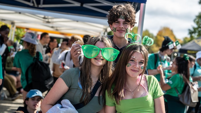 Trois jeunes portent des accessoires verts pour la célébration.