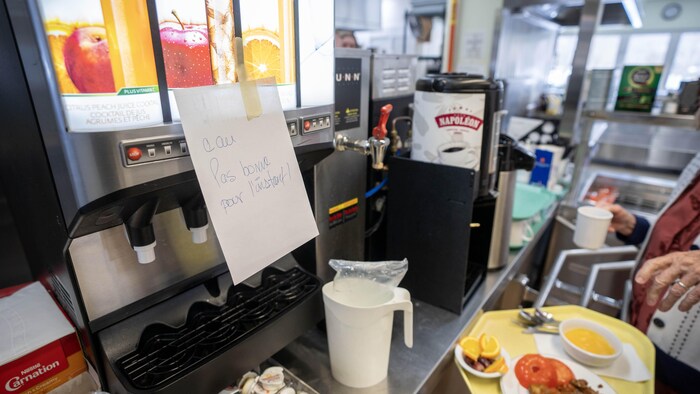 Une note indiquant que l'eau n'est pas potable est collée sur une distributrice à jus.