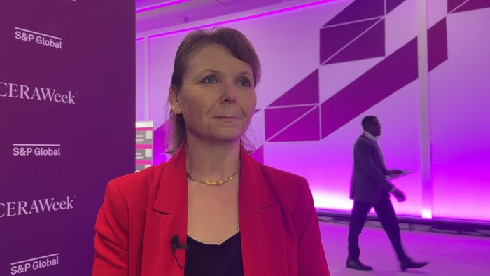 Emmanuelle Toussaint sourit devant un mur de noms de la conférence CERAWeek.