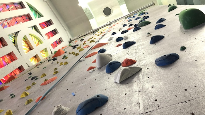 Un mur d'escalade devant les vitraux de ce qui était une ancienne église. 
