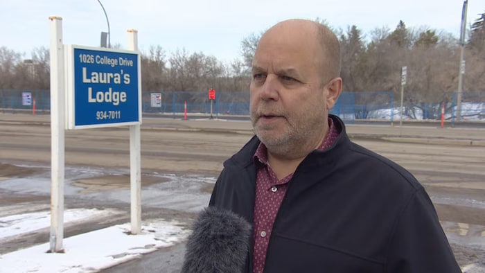 Gord Herschfeld, devant le panneau de son auberge, répond à des questions durant une entrevue.