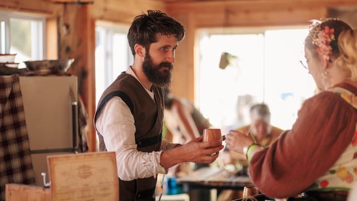 Un homme qui tend un verre en bois à une femme.