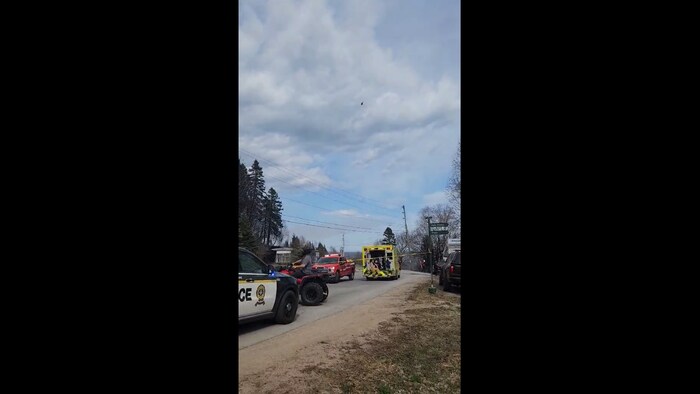 Une voiture de police, une ambulance et un véhicule du service d'incendie stationnés dans la rue.