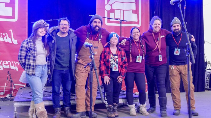 L'équipe permanente du Festival du Voyageur sourient sur scène.