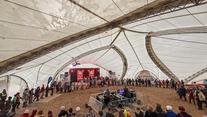 Une centaine de personnes se tiennent les mains et dansent en rond.
