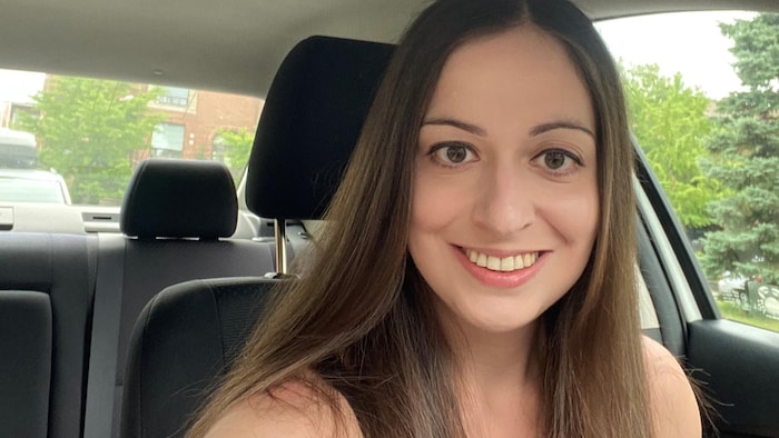 Une femme souriante qui pose à l'intérieur d'une voiture.