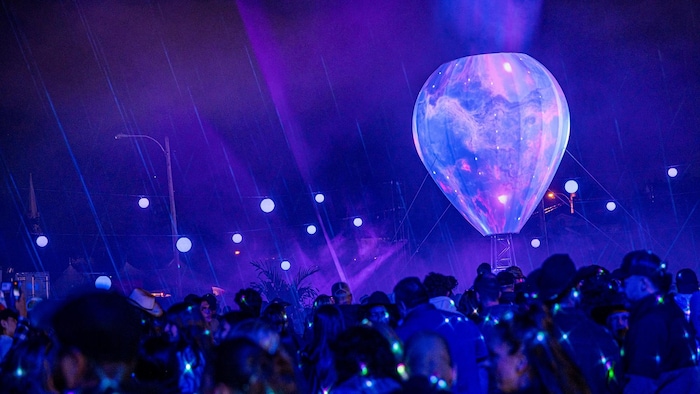 A crowd of people watch the lightening of a hot air balloon.