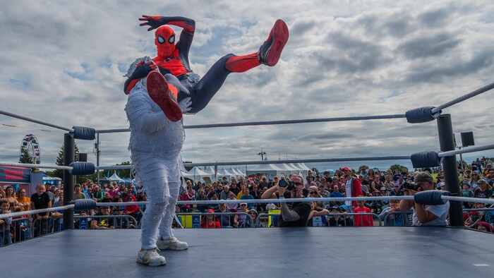 Wrestlers dressed as Spider-Man and a mummy during a fight in an arena at the Gatineau Hot Air Balloon Festival.