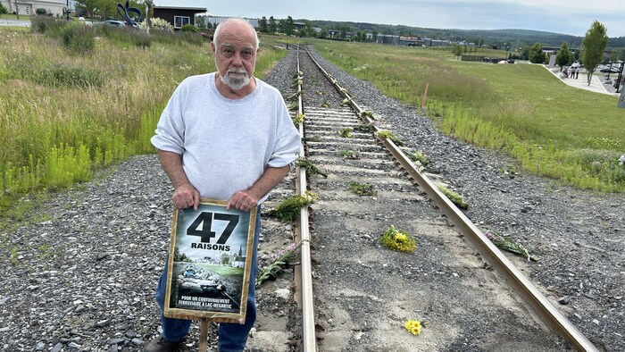 Un homme tient une pancarte qui porte la mention « 47 raisons ».