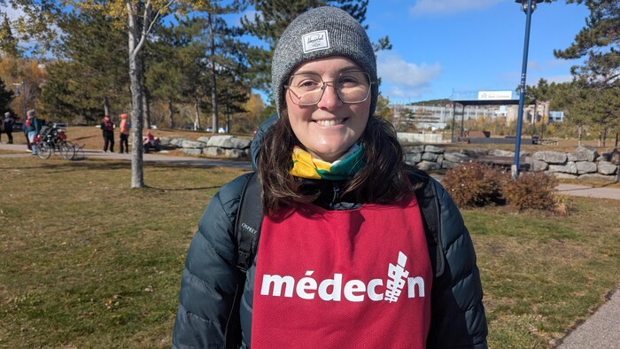 Une personne avec un dossard écrit médecin dessus à l'extérieur.