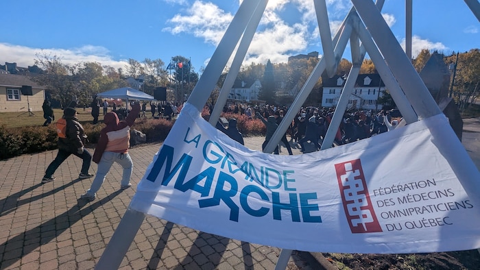 Une banderole de la Grande marche sur un monument avec des gens derrière.