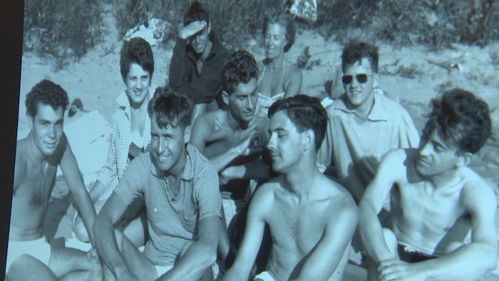 Un groupe de jeunes femmes et hommes assis sur la plage.
