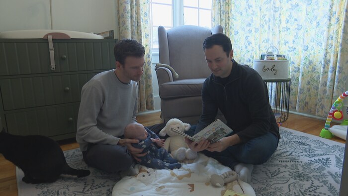 Adam Lordon et Evan Hudson lisent une histoire à leur bébé.