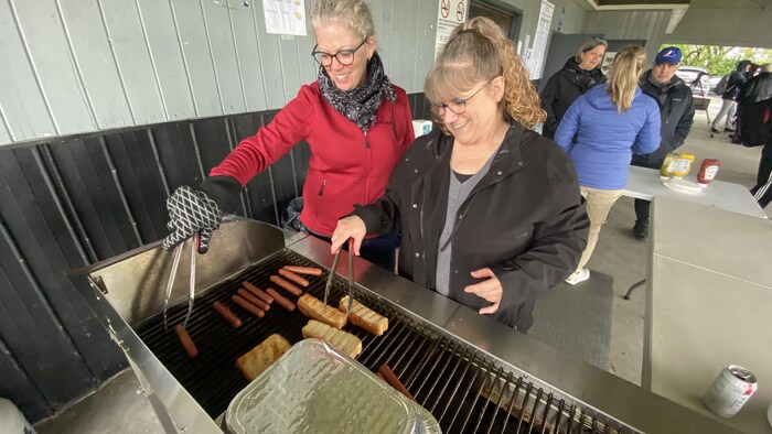 Des femmes en train de cuire des hot-dogs.