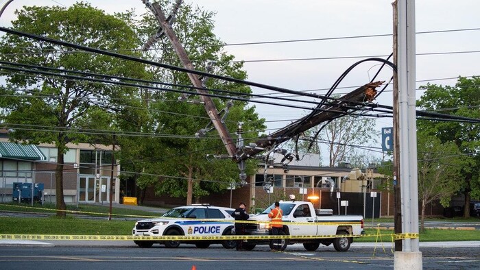 Un agent de la police d'Ottawa et un employé d'Hydro Ottawa s'affairent près de câbles électriques tombés dans une rue.