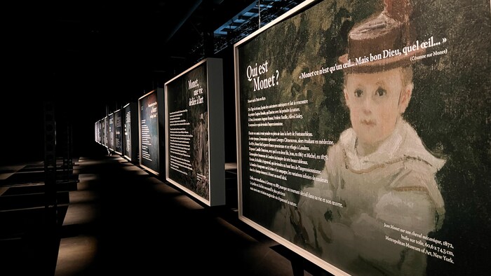 Plusieurs affiches dans une salle d'exposition qui donnent de l'information sur Claude Monet.