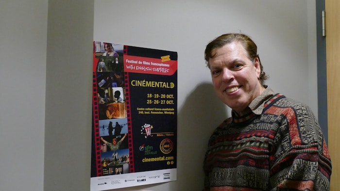Marc-François Tremblay se tient devant l'affiche de la programmation de Cinémental 2024.