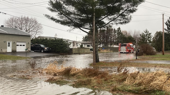 Une rue inondée avec un camion de pompier en arrière-plan.