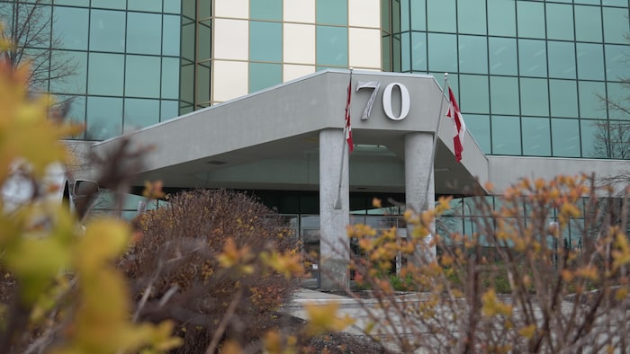 Deux drapeaux canadiens ornent l'entrée d'un édifice.