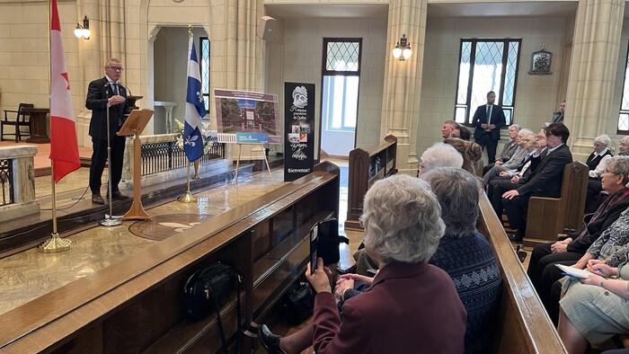 Un homme parle à des gens dans une chapelle.