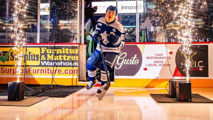 Un joueur embarque sur la glace au milieu de feux d'artifices.