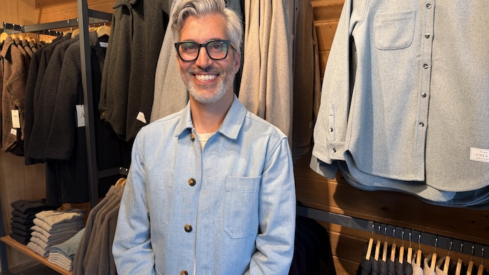 Jeff Papa sourit devant un présentoir de vêtements de sa marque.