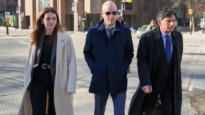 Trois personnes marchent sur un trottoir.