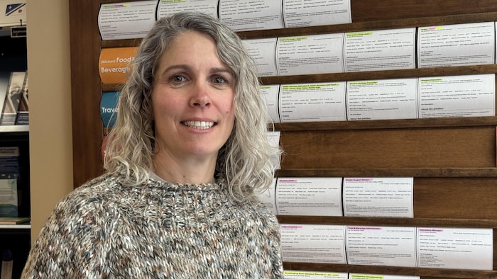 Reinira Lankhuijzen sourit devant le tableau d'affichage des offres d'emploi au Centre d'emploi de Canmore. 