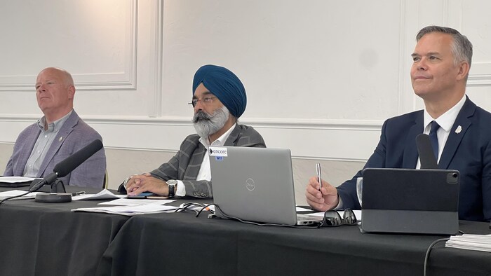 Des personnes assises devant des ordinateurs écoutent.