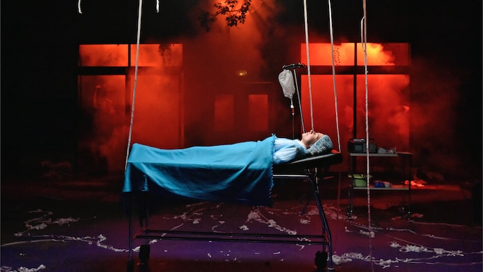 Une scène de la pièce de théâtre «La vie est une fête» où une femme est couchée sur une civière.