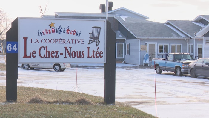 Vue d'extérieur de la Coopérative Le Chez Nous. Au premier plan, la pancarte indiquant l'établissement.