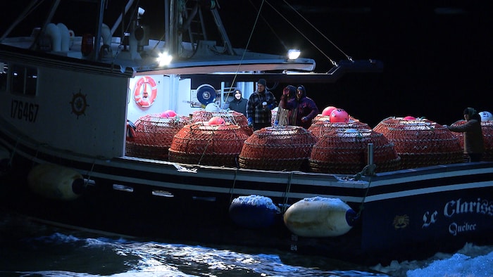 Un bateau de pêche au crabe chargé de casiers quitte le port de Rimouski.