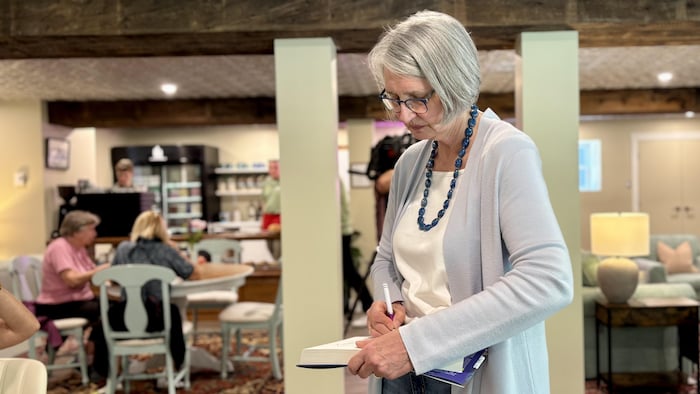 Louise Penny qui dédicace un roman dans le café La Joie de Lire.