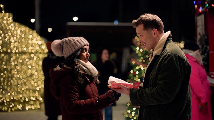 Un homme qui thin   une pâtisserie queue de castor à une femme en hiver.