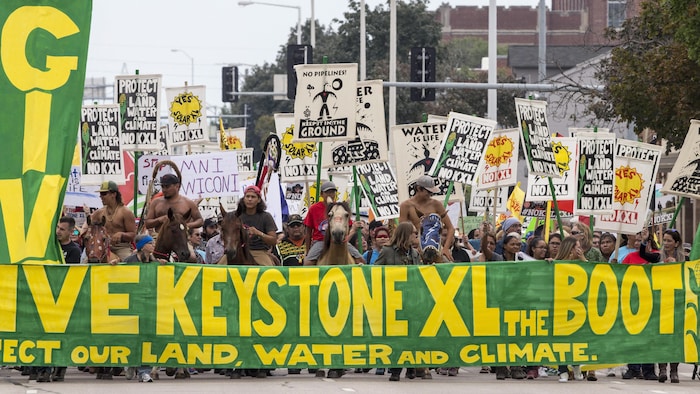 Des dizaines de manifestants marchent et sont à cheval derrière une bannière s'opposant à Keystone XL dans cette photo datant de 2017. 