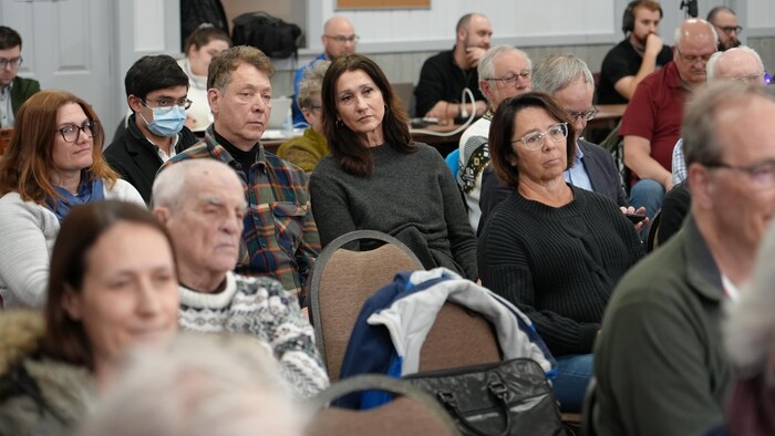 Des gens assis sur des chaises écoutent