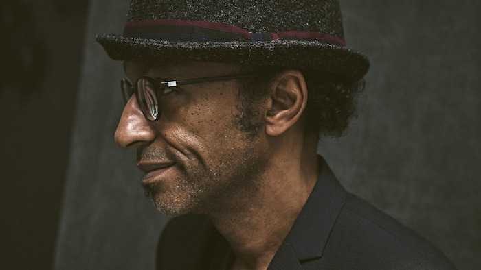Profil d'un homme qui pose. Il porte un chapeau.