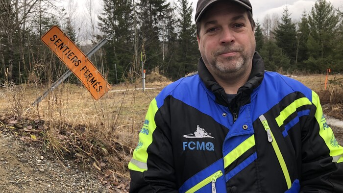 Marc Lachance devant une affiche indiquant "sentiers fermés". 