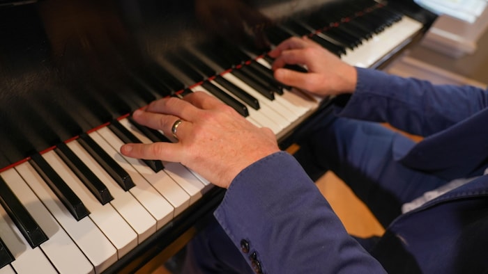 Gros plan des mains d'un homme qui jour du piano.