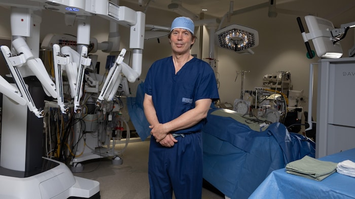 Un homme qui pose debout dans une salle d'opération médicale.