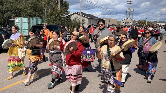 Une foule marche dans la rue. Les personnes à l'avant tiennent des tambours traditionnels.