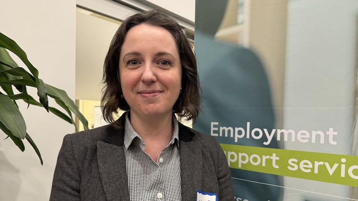 Marie Couderc-Grau sourit devant une pancarte parlant d'emploi, à Calgary, le 15 janvier 2026.