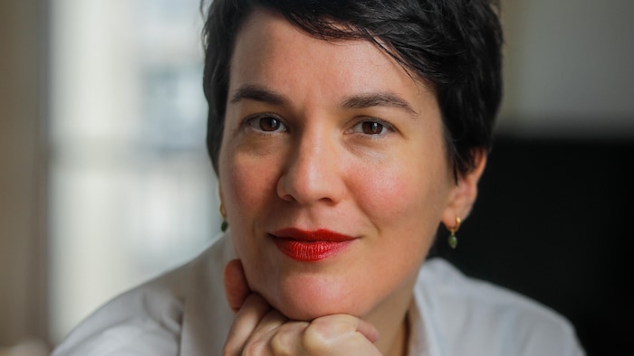 Portrait de Marie-Eve Lacasse qui fixe la caméra, la tête appuyée sur les jointures de sa main droite.