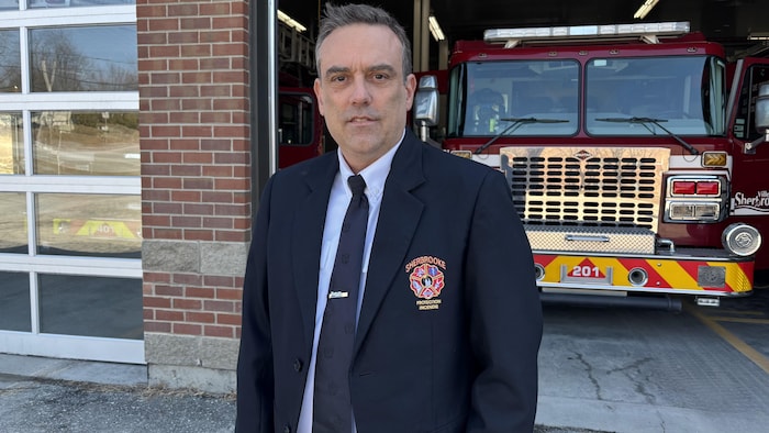 Un homme devant une caserne de pompiers.