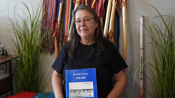 Maureen Belanger tient un livre sur l'histoire de Ile-à-la crosse.