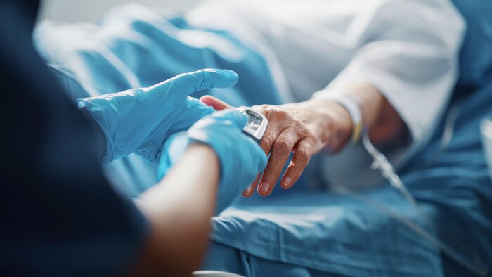 Gros plan des mains d'un médecin avec des gants qui tiennent la main d'un patient.
