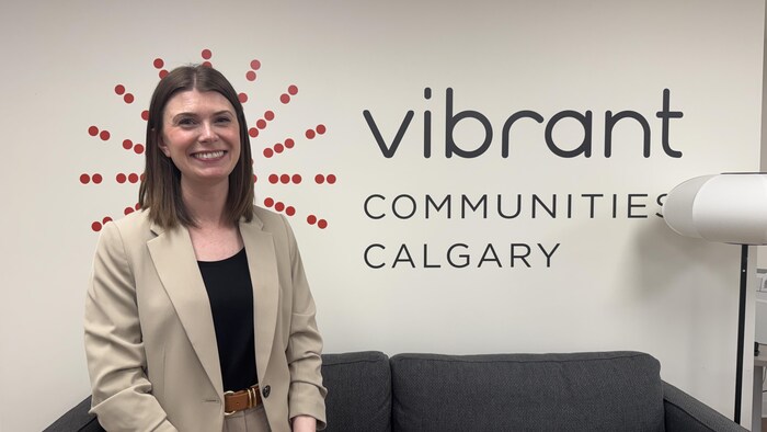 Michelle James se tient devant un mur avec le nom de l'organisme Vibrant Communities Calgary.