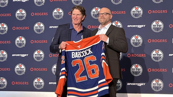 Babcock en compagnie du directeur général tenant un chandail aux couleurs des OIlers avec son nom et le numéro 26 au dos. 23 juin 2026.